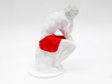 a statue of a man sitting on a rock with a red bag