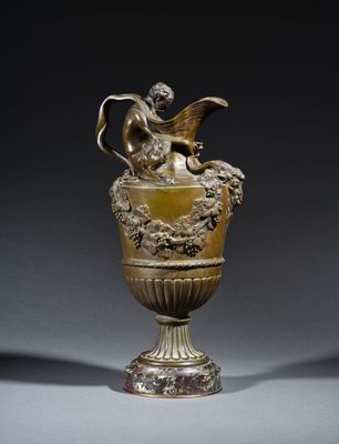 an antique bronze vase with a winged figure on top of it