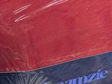 a red bag sitting on top of a bed next to a pillow