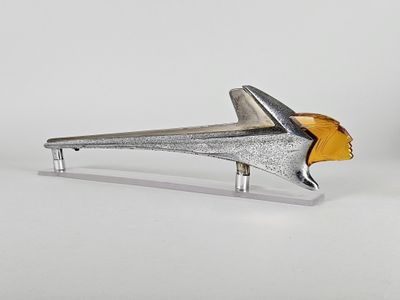 un objet en forme d'avion, de couleur argentée et dorée, posé sur une surface blanche