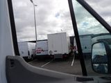 vehicles parked in a parking lot with a cloudy sky in the background