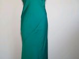 une robe verte posée sur un mannequin contre un mur blanc
