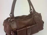 quelqu'un tient un sac à main marron posé sur une surface blanche
