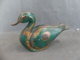 a green and gold duck figurine sitting on a gray surface