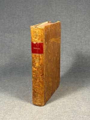 an old book sitting on top of a table on a gray surface