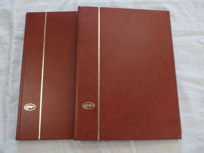 deux carnets en cuir rouge aux bords dorés, posés sur un lit