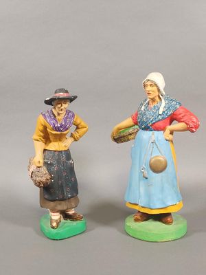 two figurines of women with hats and aprons standing next to each other
