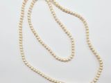 un collier de perles blanches avec un fermoir en or sur fond blanc
