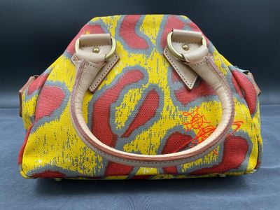 yellow and red handbag with handles on a blue surface