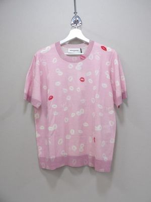 a pink shirt with white flowers on it hanging on a hanger