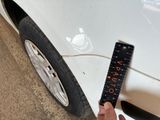 a hand that is holding a ruler in front of a car