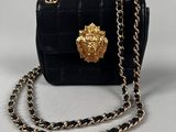 a small black purse with a gold lion head on the front