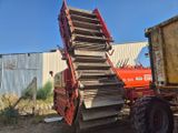 un tracteur rouge garé à côté d'un tas de bois