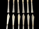 a set of eight silverplated spoons and a knife on a black background