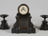 une petite horloge posée sur une table, à côté de deux tabourets