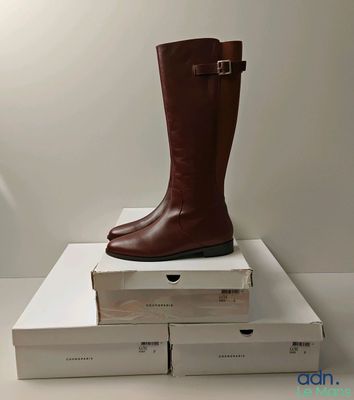 une paire de bottes marron posée sur des cartons