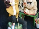 a figurine of a woman sitting on a chair with a skeleton in the background