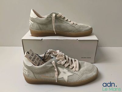 des baskets dans une boîte posée sur une table, avec une boîte de chaussures en arrière-plan