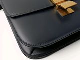 a black purse with a gold handle on a white surface