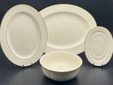 four pieces of white and gold dinnerware on a table