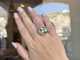 the woman is wearing a ring with a green stone on it