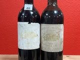 two bottles of wine on a table with a red wall in the background