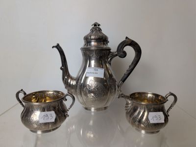 three silver teapots and two silver cups on a table