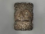 an antique silver cigarette case with a picture of a castle on it