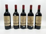four bottles of wine are lined up on a white surface