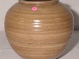 un vase marron sur lequel est collé un autocollant rose