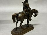 statue of a man riding a horse on a wooden base