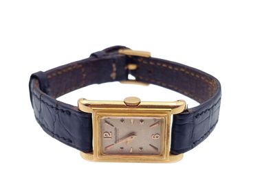 une photo d'une montre-bracelet avec un boîtier en or et un bracelet en cuir bleu