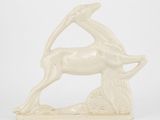 une sculpture blanche représentant une antilope posée sur un rocher