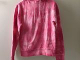 a pink hoodie hanging on a hanger against a white wall