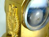 a gold clock with a glass face on a table