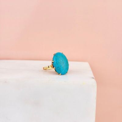 a close up of a turquoise stone ring on a marble block