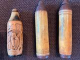 trois bouteilles en bois ornées de sculptures, posées sur une table