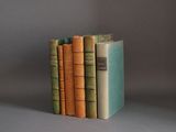 three books are stacked on top of each other on a gray surface