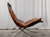 a brown leather chair sitting on top of a wooden floor