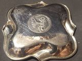 a silver plate with a coin on it on a table
