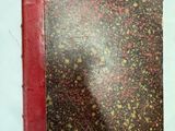 un vieux livre à la couverture rouge posé sur une table blanche