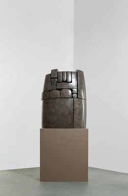 une sculpture dans un coin d'une pièce, avec une boîte posée par terre