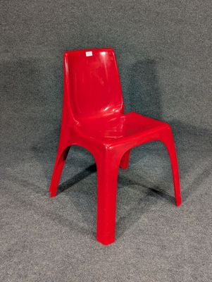 une chaise en plastique rouge posée sur une surface grise