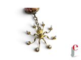 a person holding a keychain with a gold spider on it