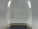 a glass clochet with a gold base on a table