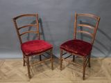 pair of wooden chairs with red upholstered cushions against a gray wall