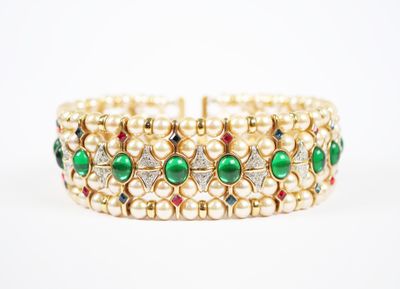 un gros plan sur un bracelet en or orné de perles vertes et blanches