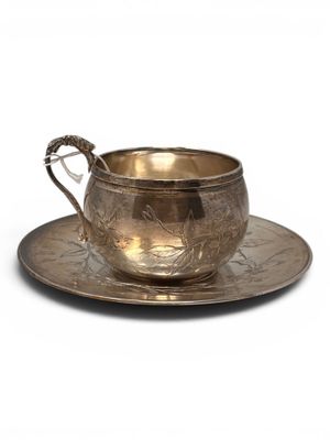 an antique silver cup and saucer on a saucer