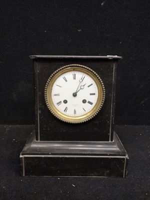 une petite horloge posée sur une table noire