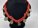 un collier composé de pièces de monnaie et de perles de corail, présenté sur un mannequin noir